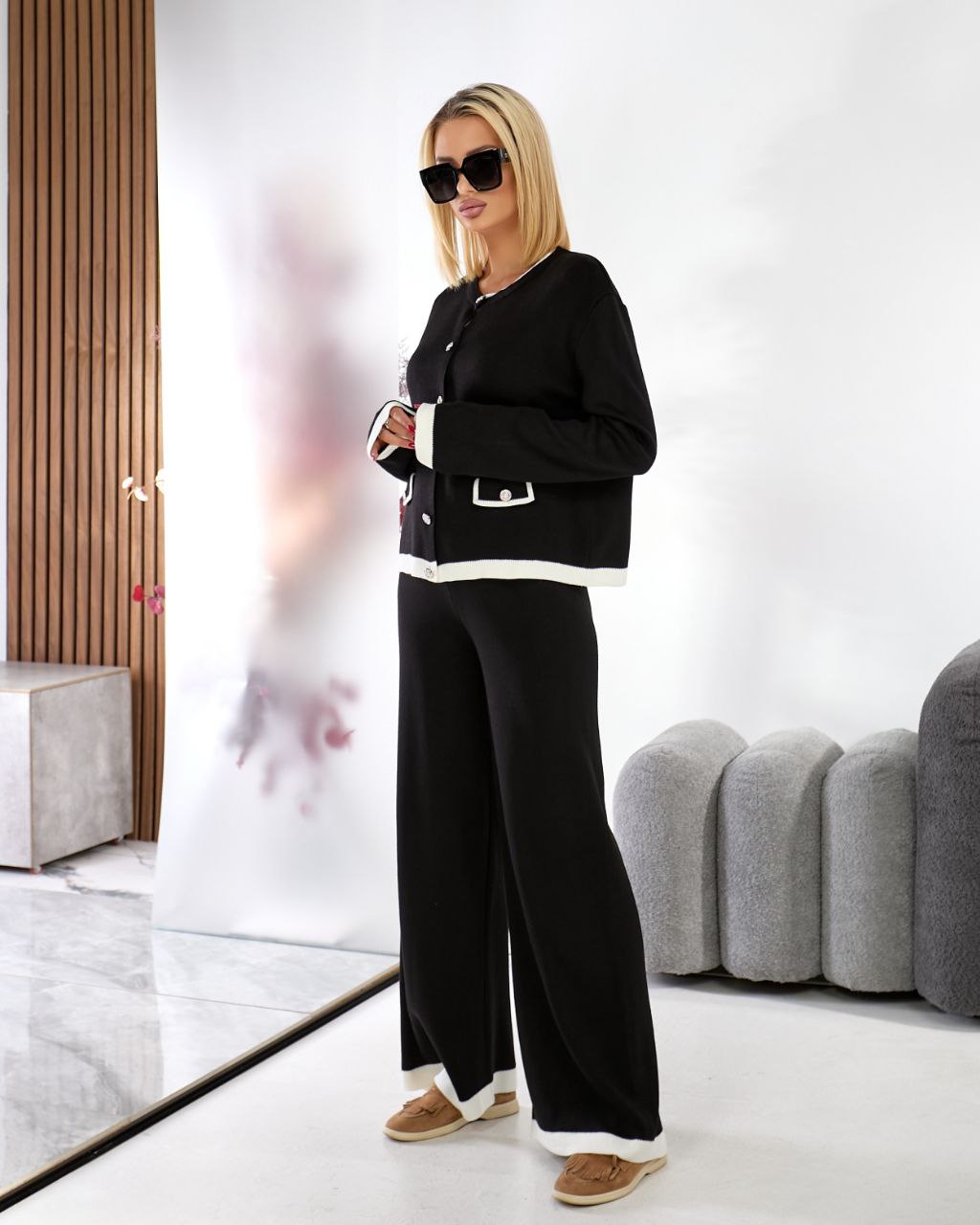 Woman in a black outfit standing in a modern interior setting