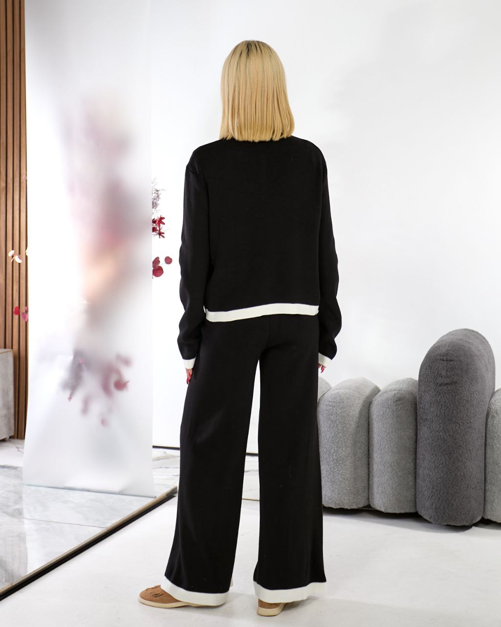 Woman wearing a black outfit with white trim in a modern room.