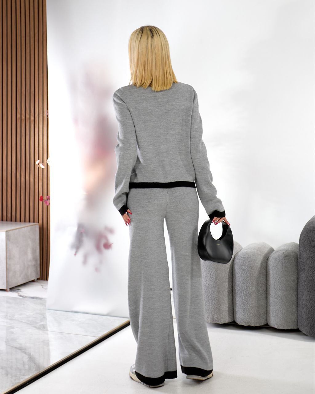 Woman in a gray outfit standing in a modern living room.