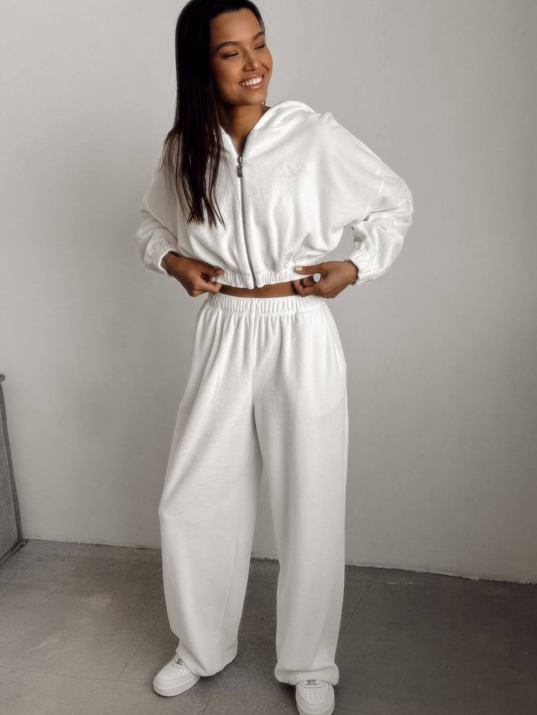 Woman wearing a white tracksuit against a plain background
