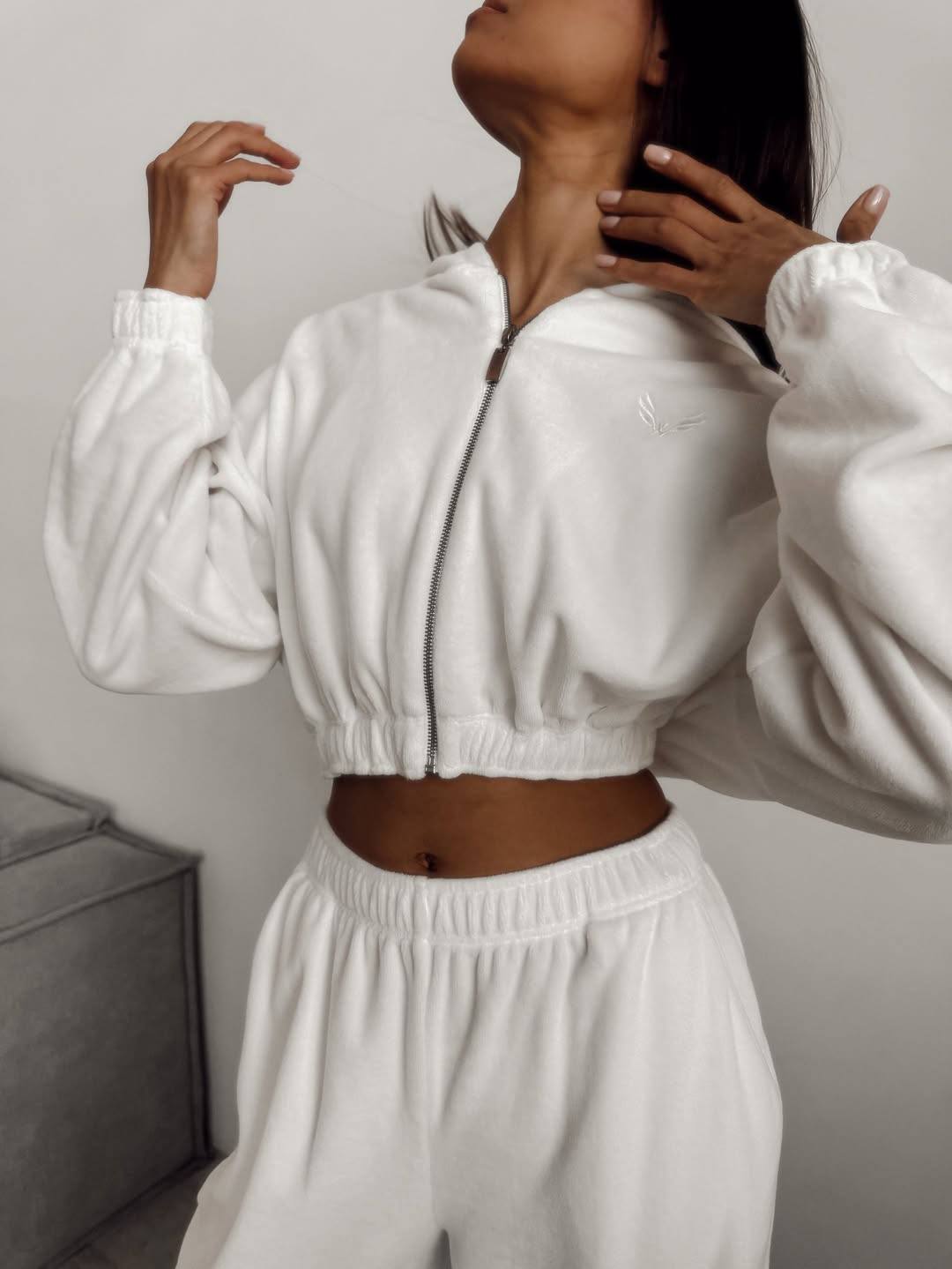 Person wearing a white tracksuit against a neutral background