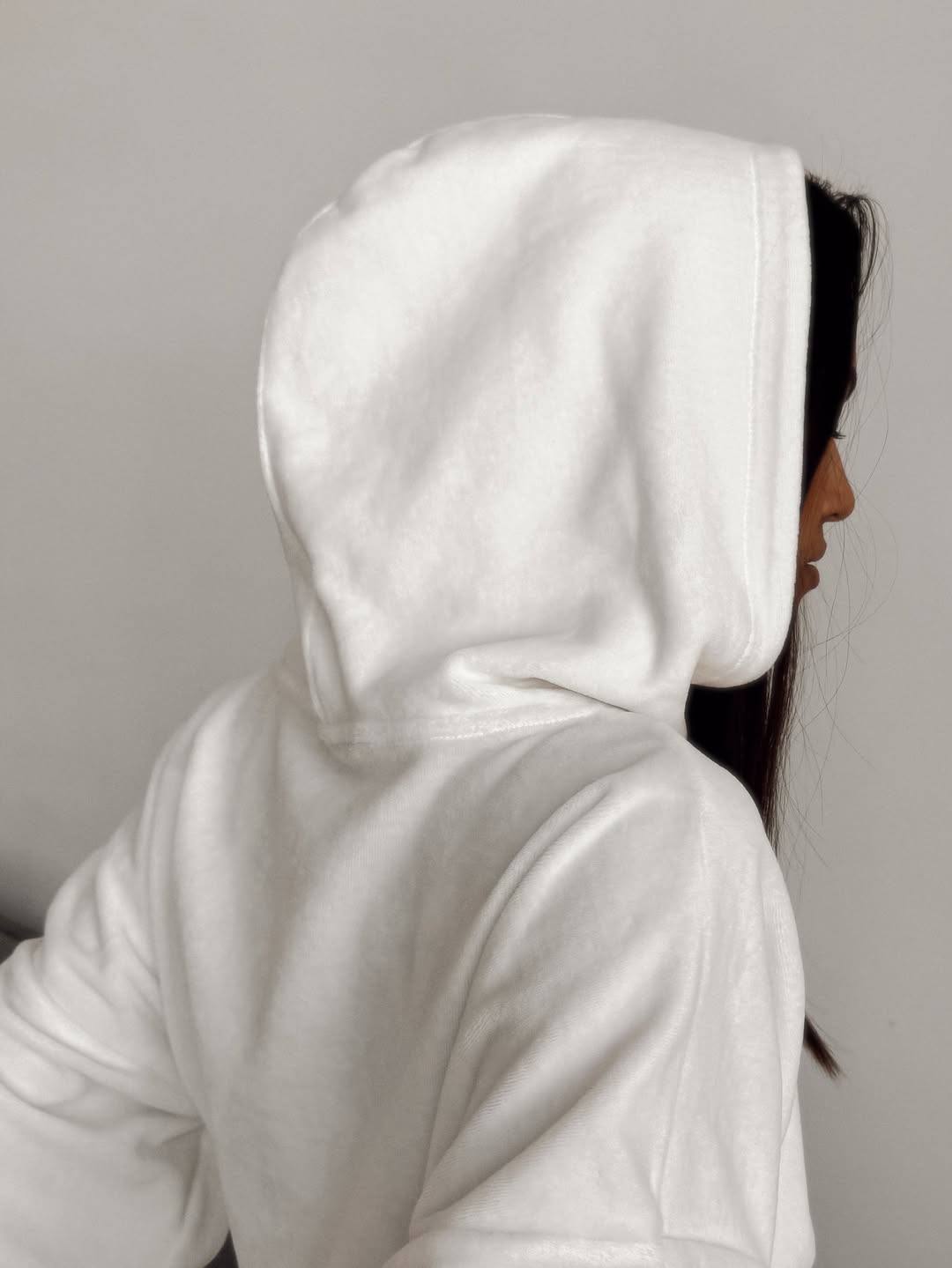Person wearing a white hoodie against a plain background