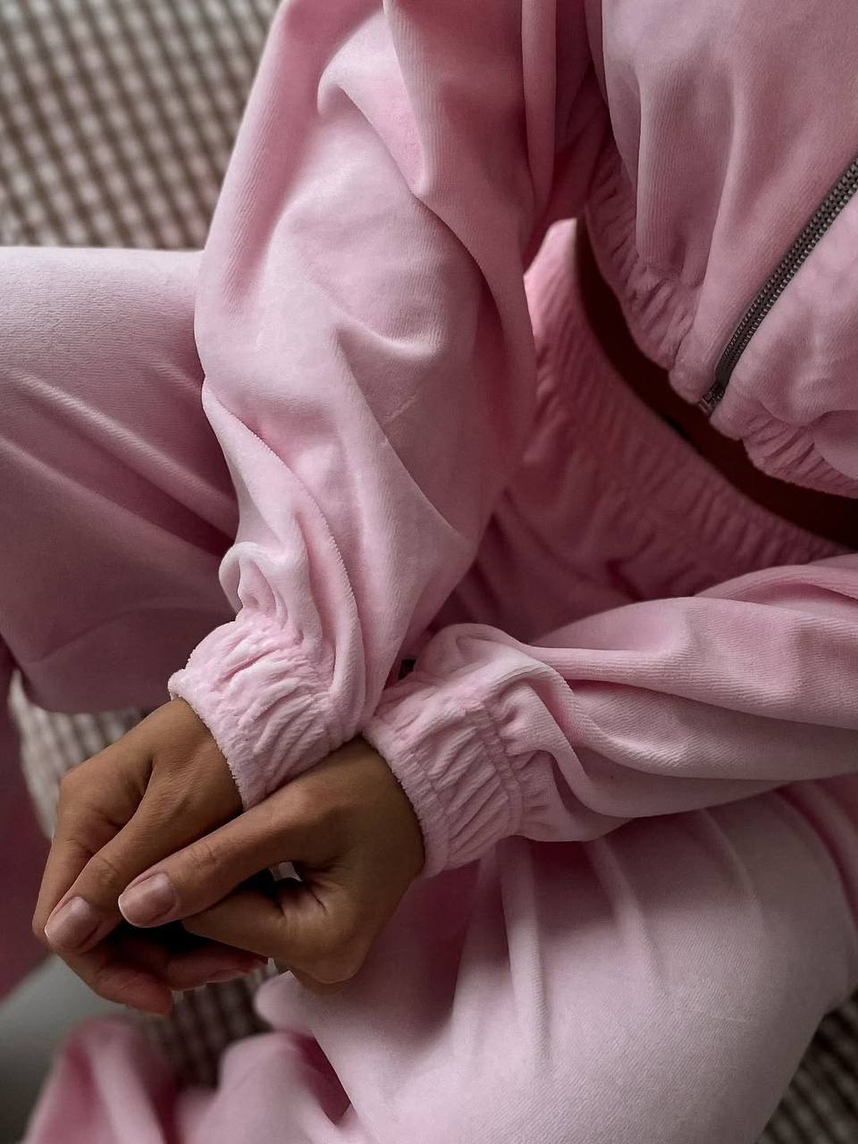 Person wearing a pink tracksuit sitting on a checkered surface