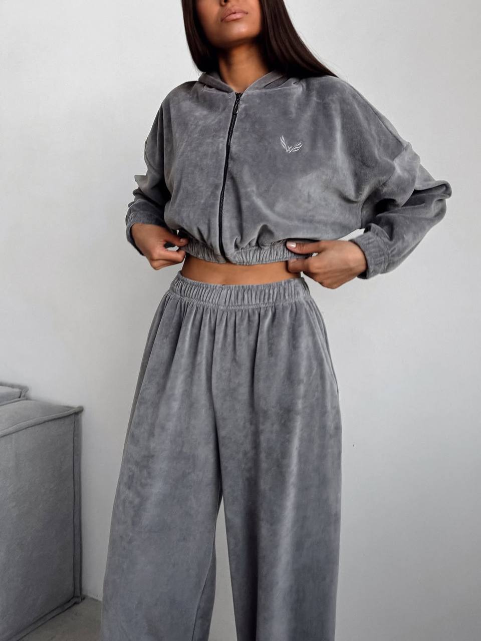 Person wearing a gray tracksuit with a small logo on a white background