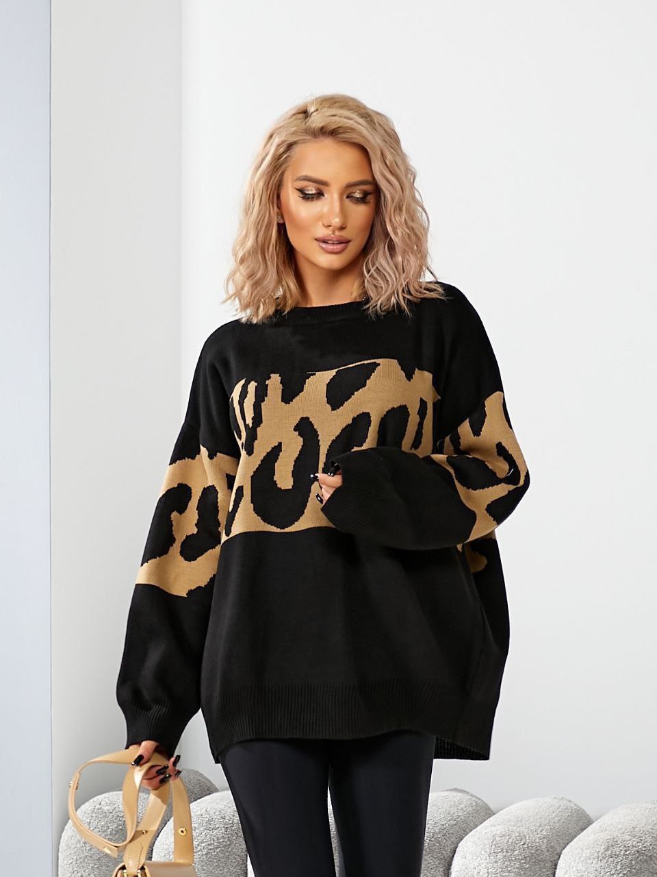 Woman wearing a black sweater with a leopard print pattern on a white background