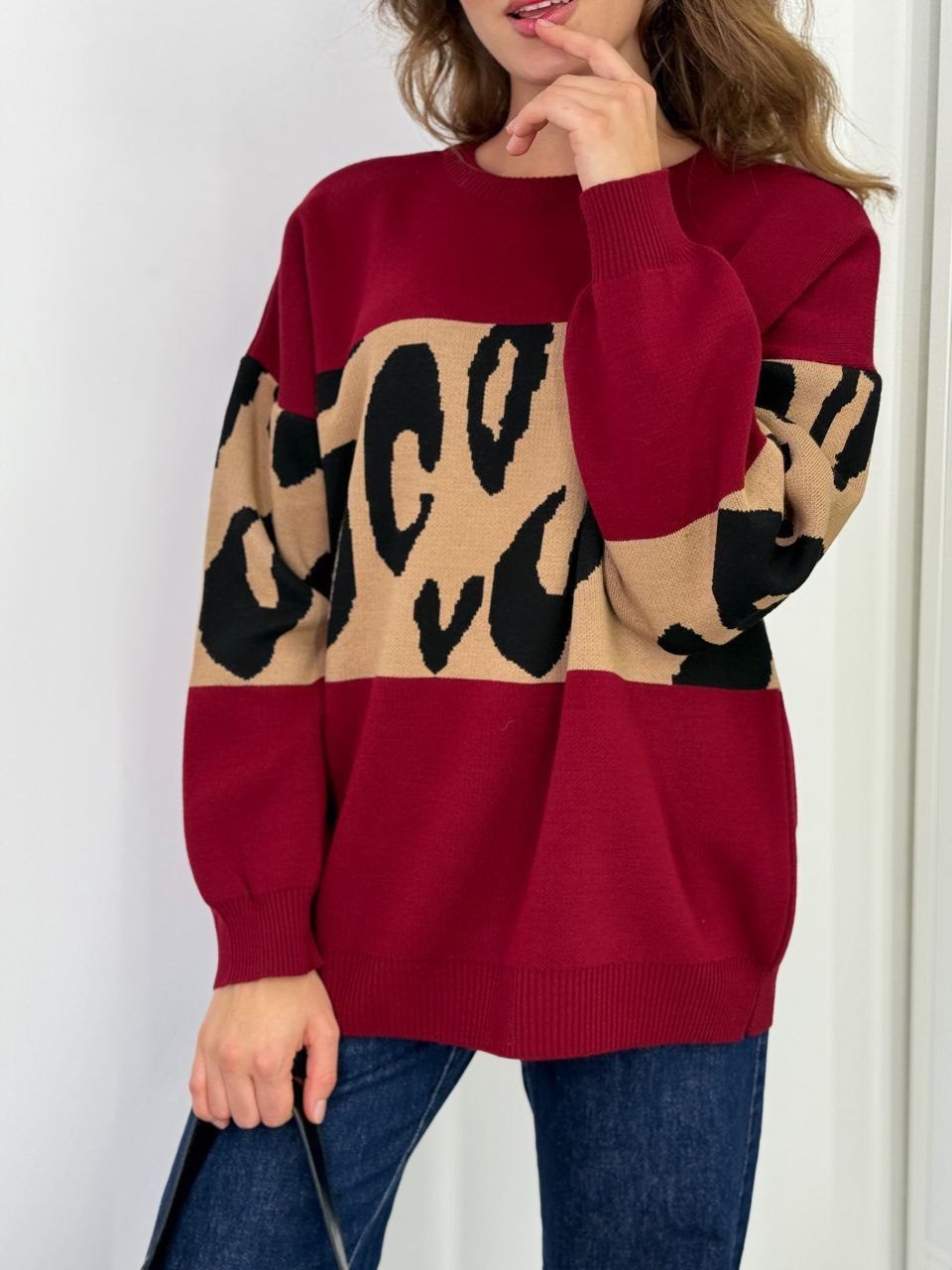 Person wearing a red sweater with a leopard print design on a white background