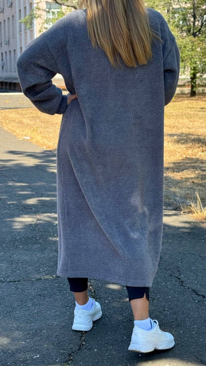 Person wearing a long gray cardigan on a street