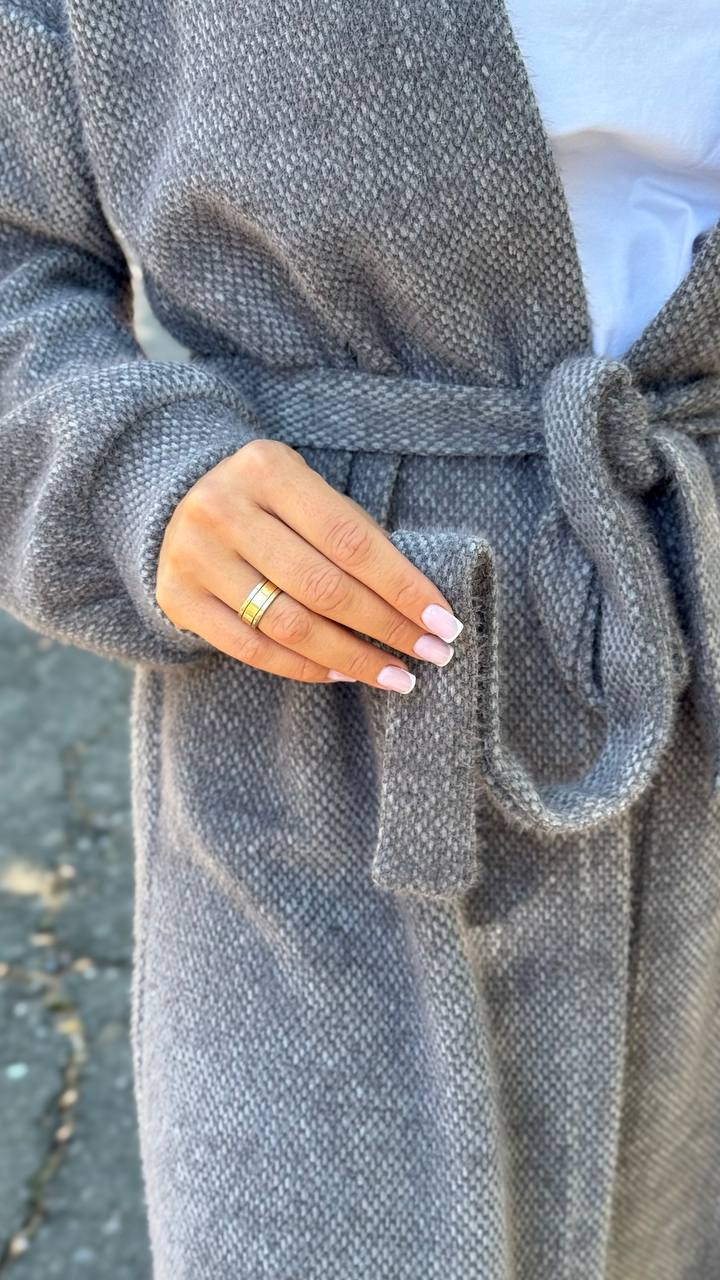 Person wearing a gray coat with a close-up of their hand holding the fabric.