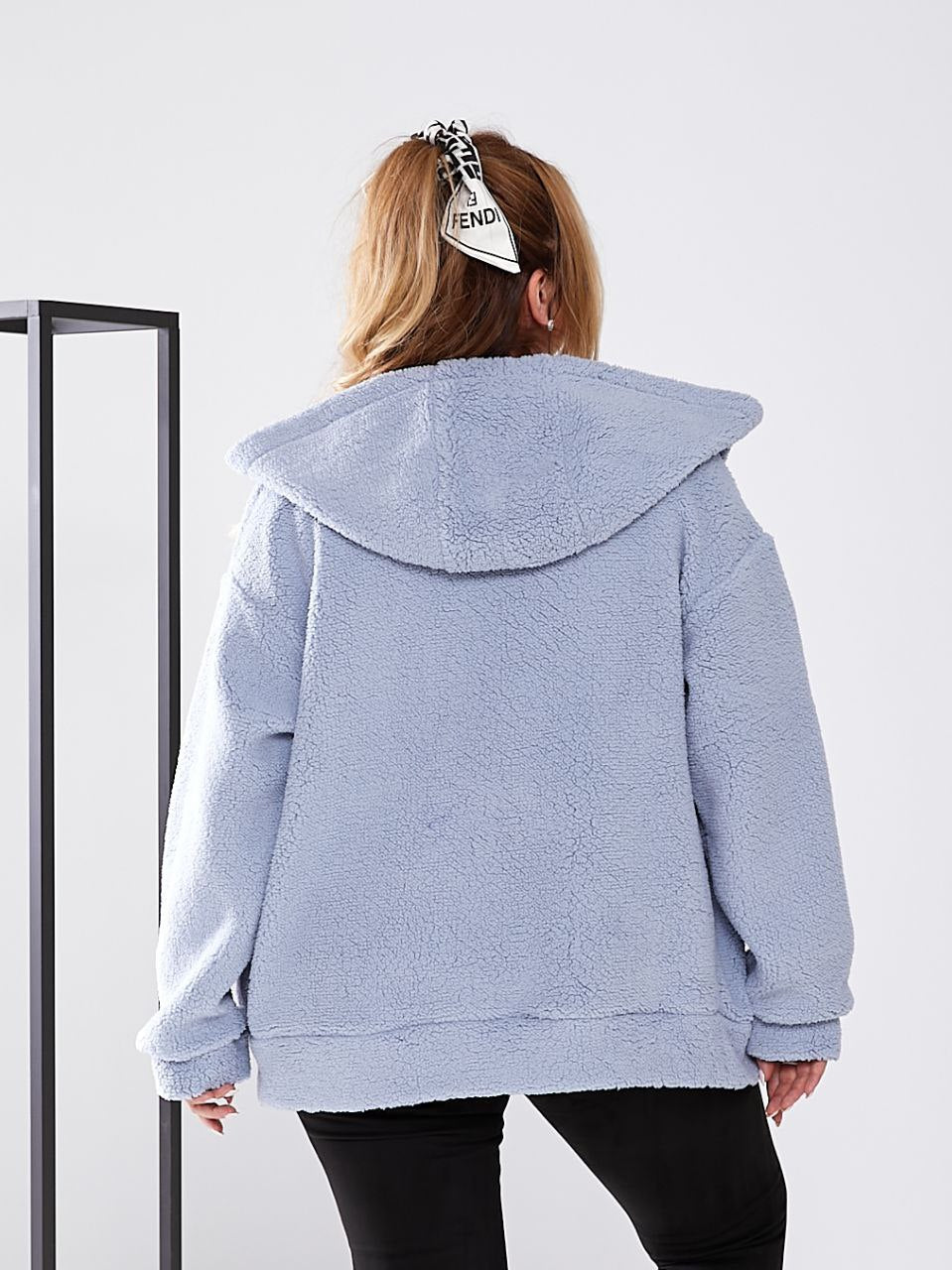 Person wearing a light blue fleece jacket with a hood on a white background
