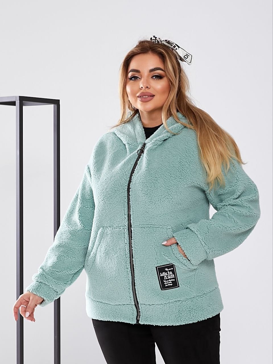 Woman wearing a light blue fleece jacket with a brand logo on a white background