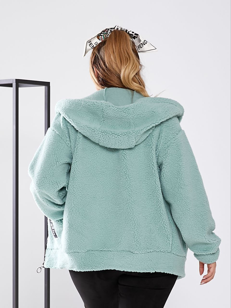 Person wearing a light blue fleece jacket with a hood on a white background