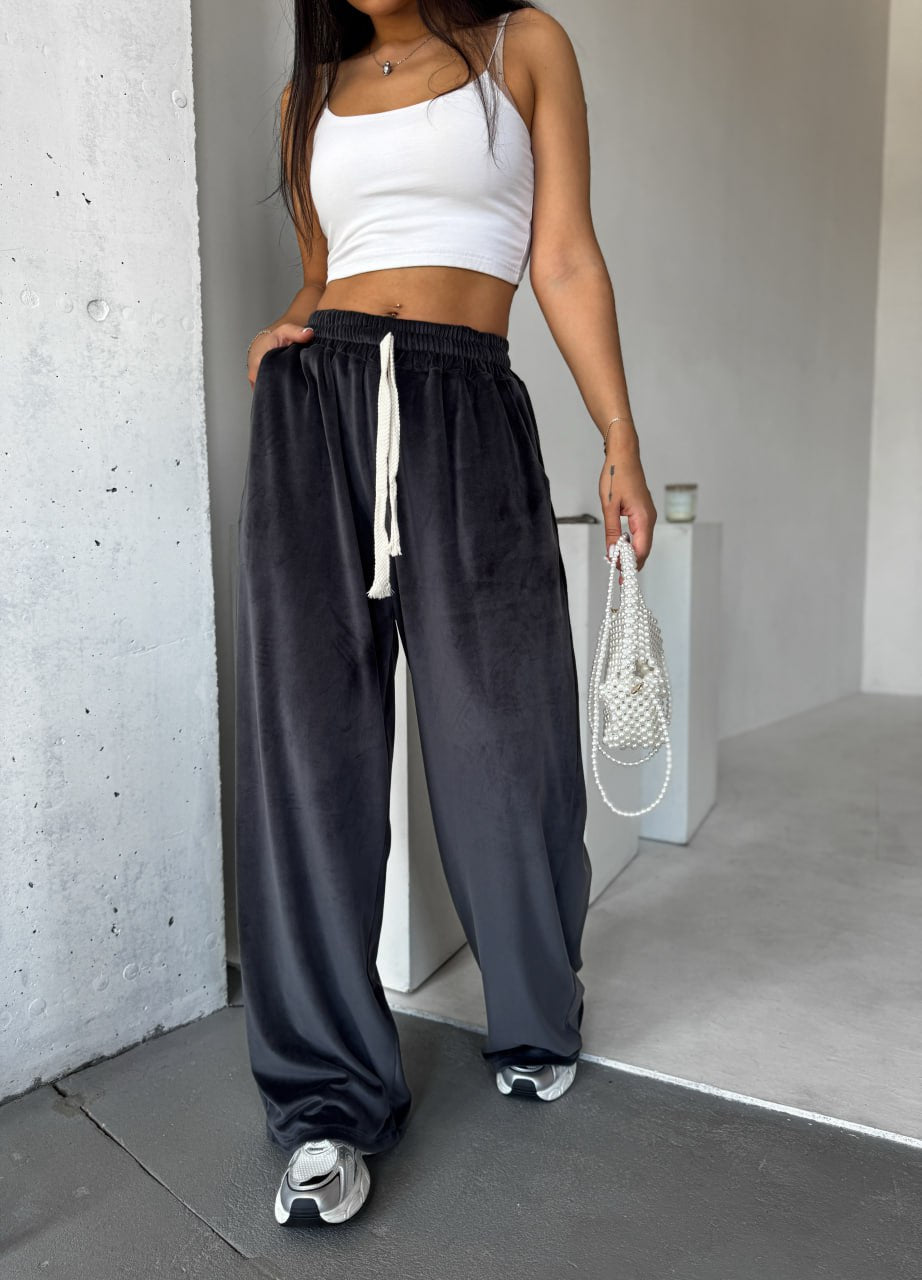 Person wearing a white crop top and black wide-leg pants in an indoor setting.