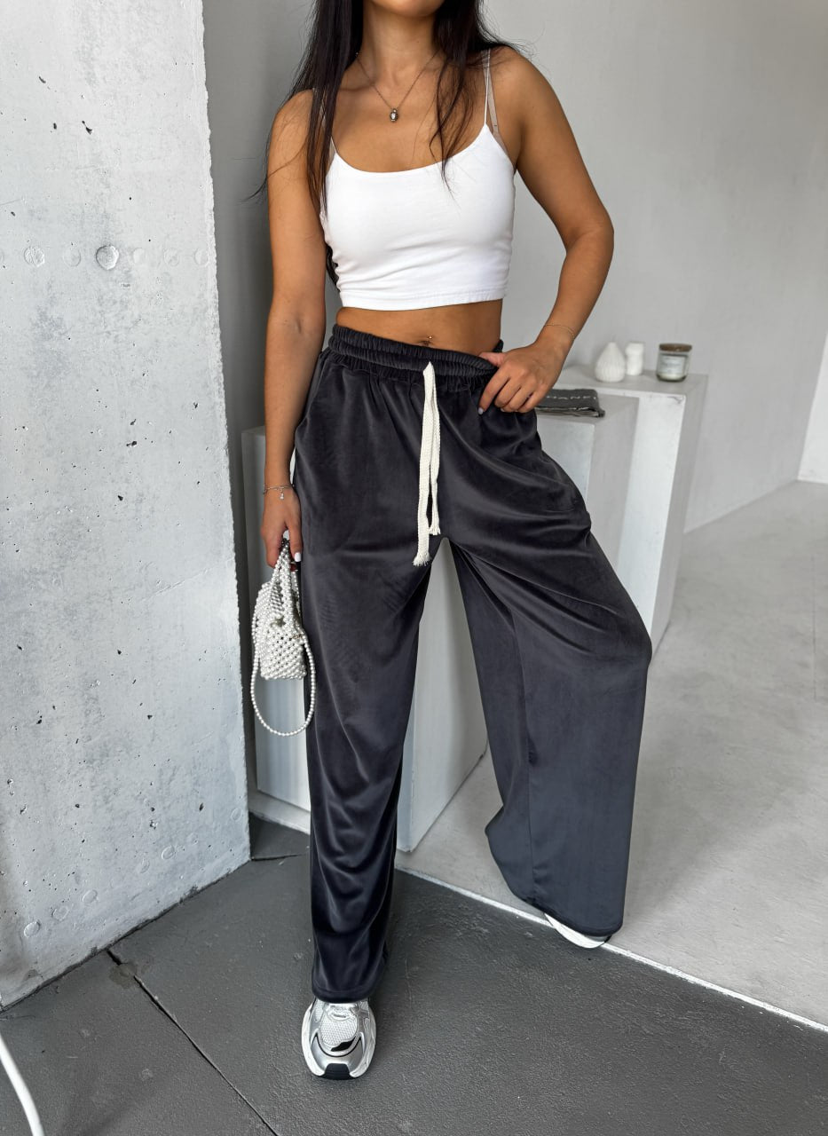Person wearing a white crop top and black wide-leg pants in an indoor setting.
