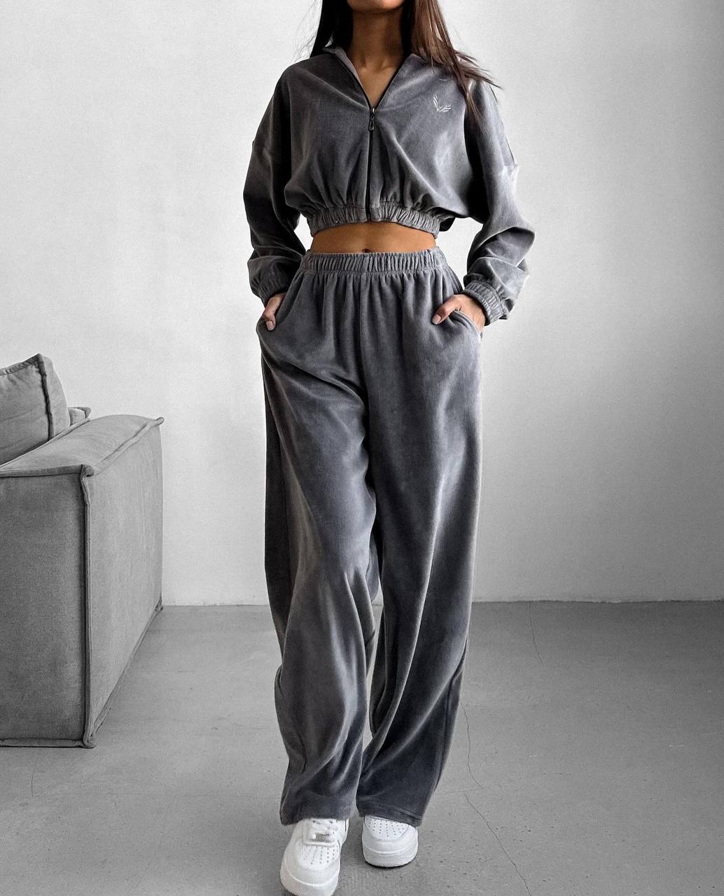 Person wearing a gray tracksuit in a minimalistic room.