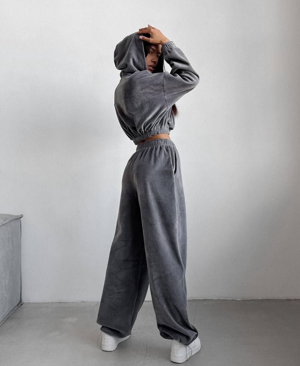 Person wearing a gray tracksuit against a plain background