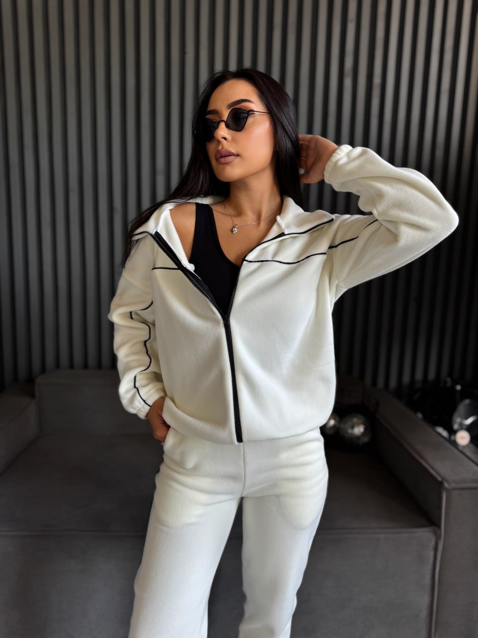Woman wearing a white tracksuit with black accents in a modern interior setting