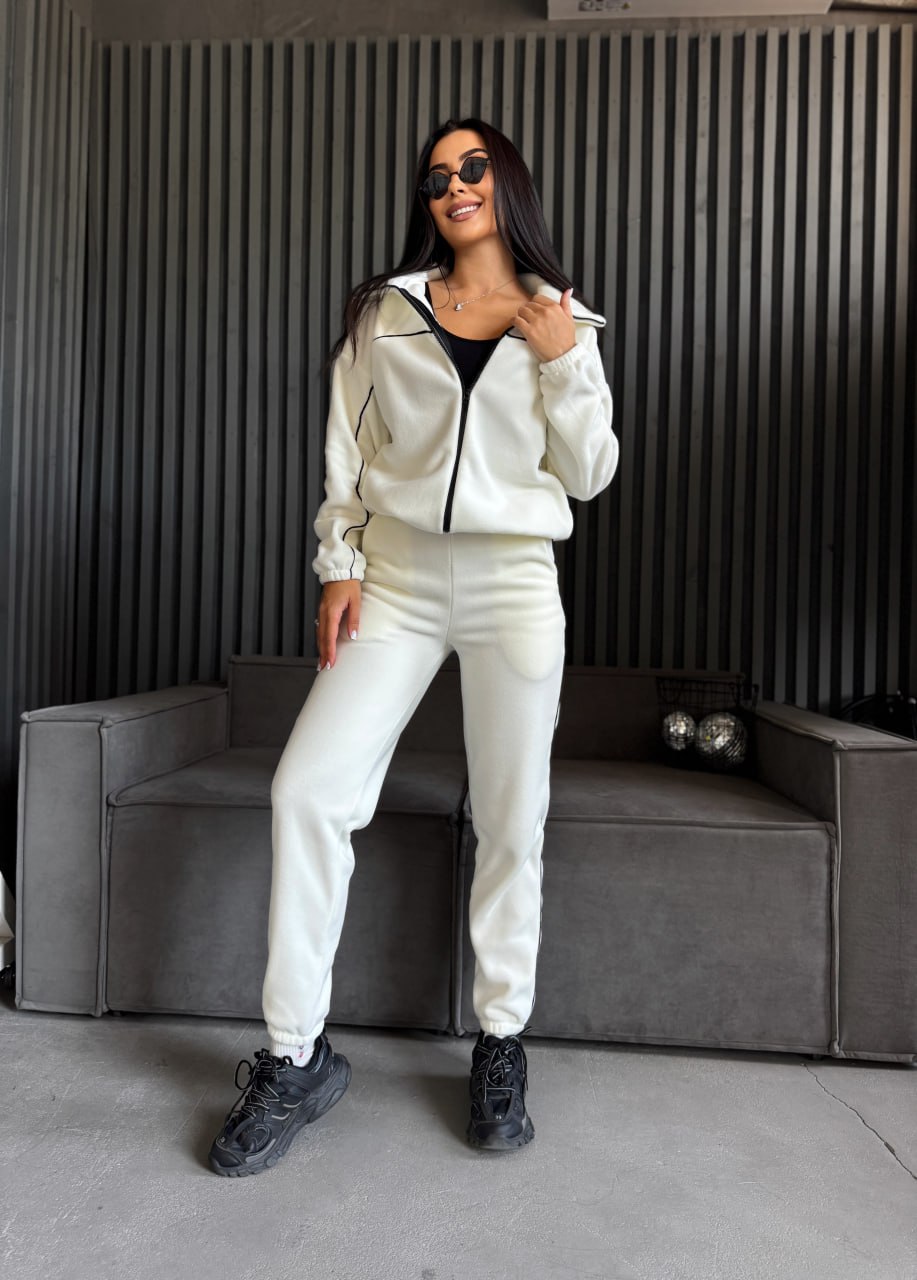 Woman in a white tracksuit standing in a modern interior setting