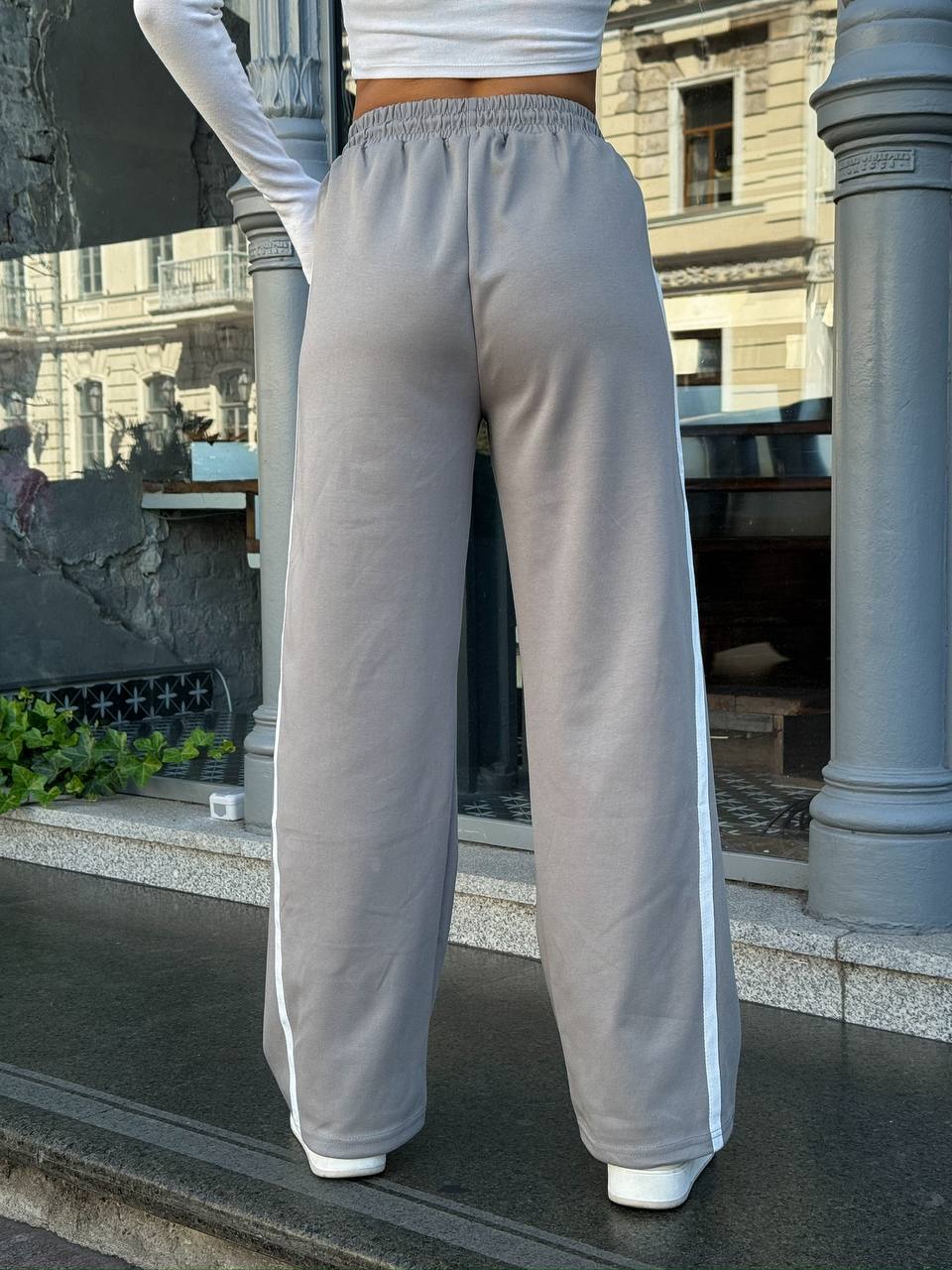 Person wearing gray sweatpants with white stripes in an urban setting