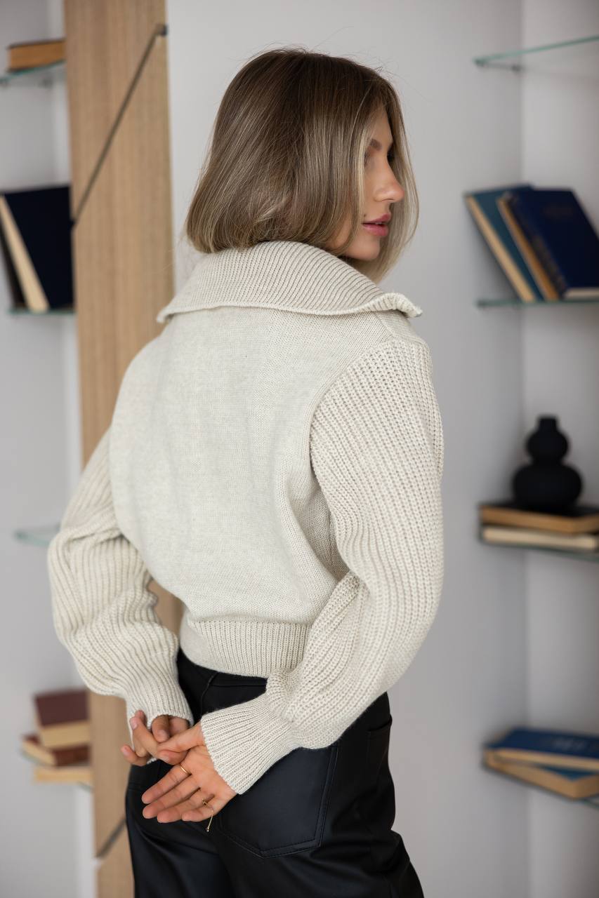 Woman wearing a beige knitted sweater in an indoor setting