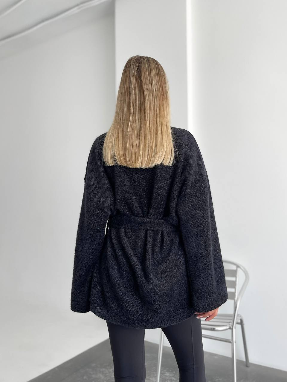 Person wearing a dark coat in a minimal indoor setting