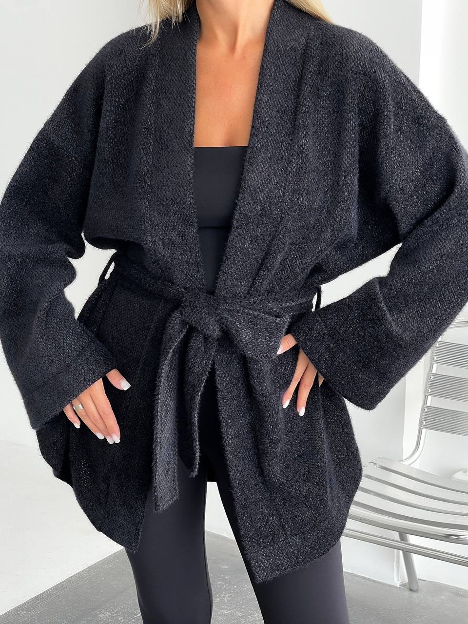 Person wearing a dark gray robe with a belt in a minimal indoor setting