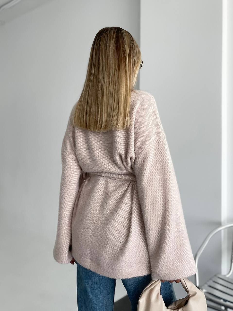 Person wearing a light pink coat with a plain background