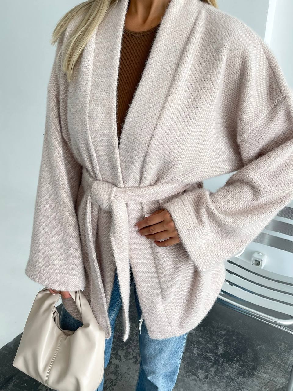 Person wearing a beige robe with a plain background