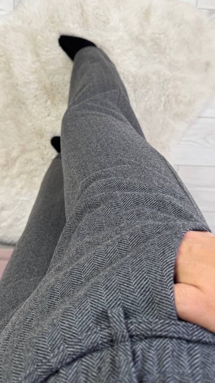 Gray pants worn by a person on a light-colored carpet