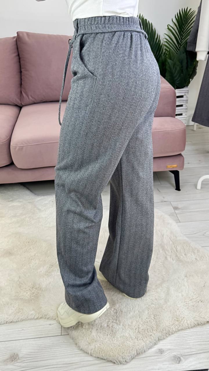 Person wearing gray wide-leg pants in a living room setting