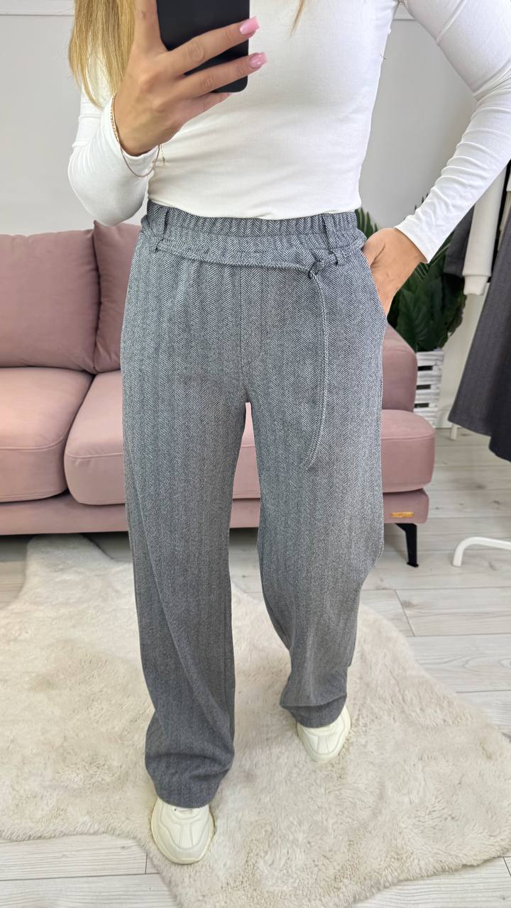Person wearing gray pants and a white top in a living room setting.