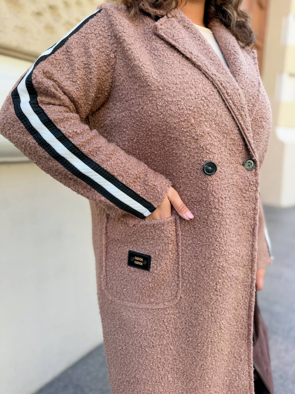 Person wearing a long, brown coat with white stripes on the sleeves.