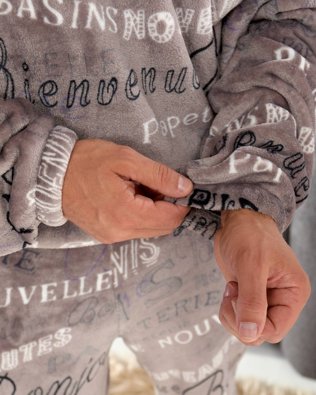 Gray fleece blanket with embroidered text held by a person