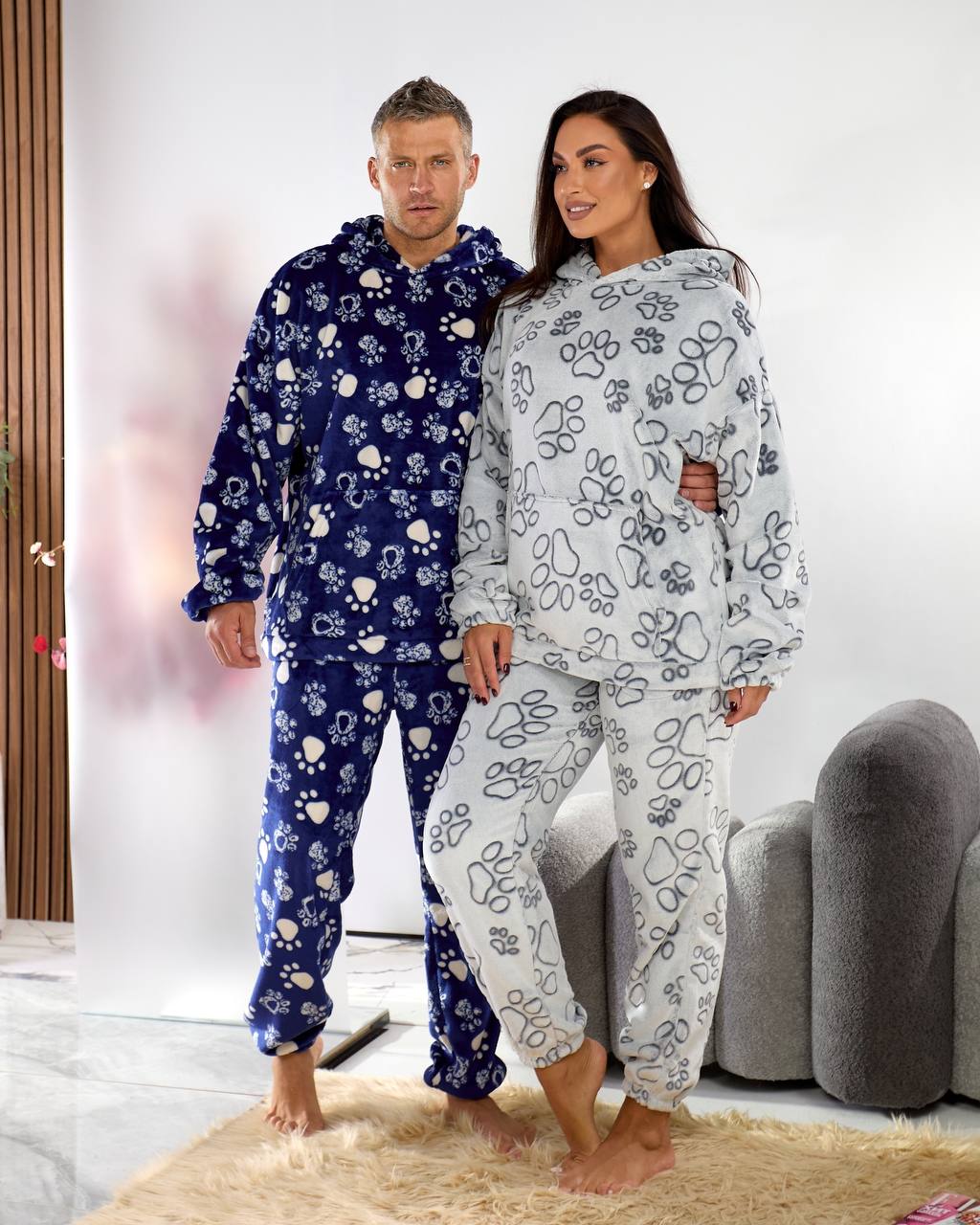 Man and woman wearing matching pajama sets with a floral pattern in a living room.