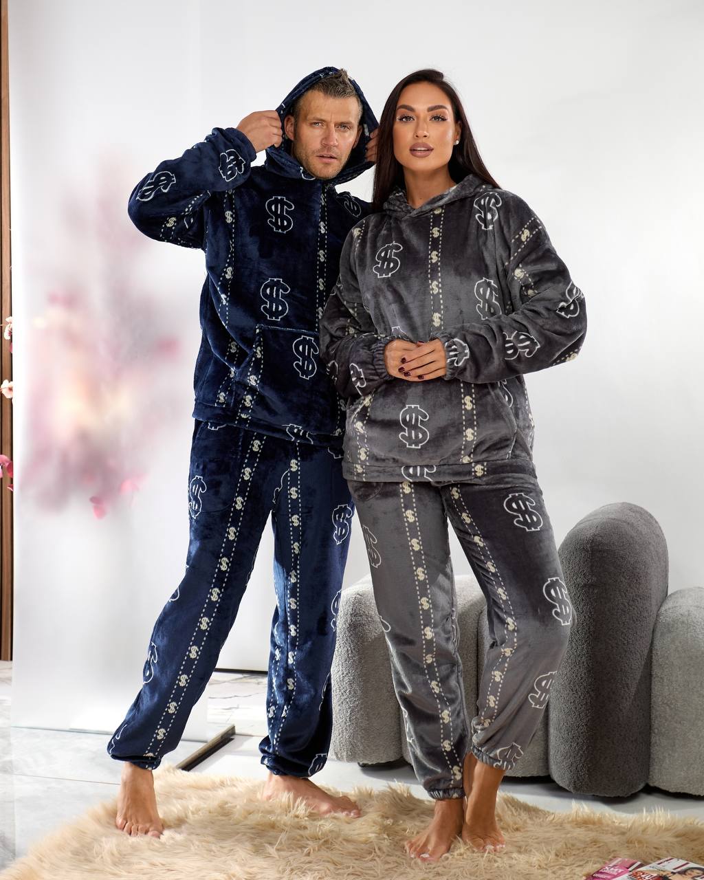 Two people wearing matching navy and gray pajama sets with a pattern, standing in a room.