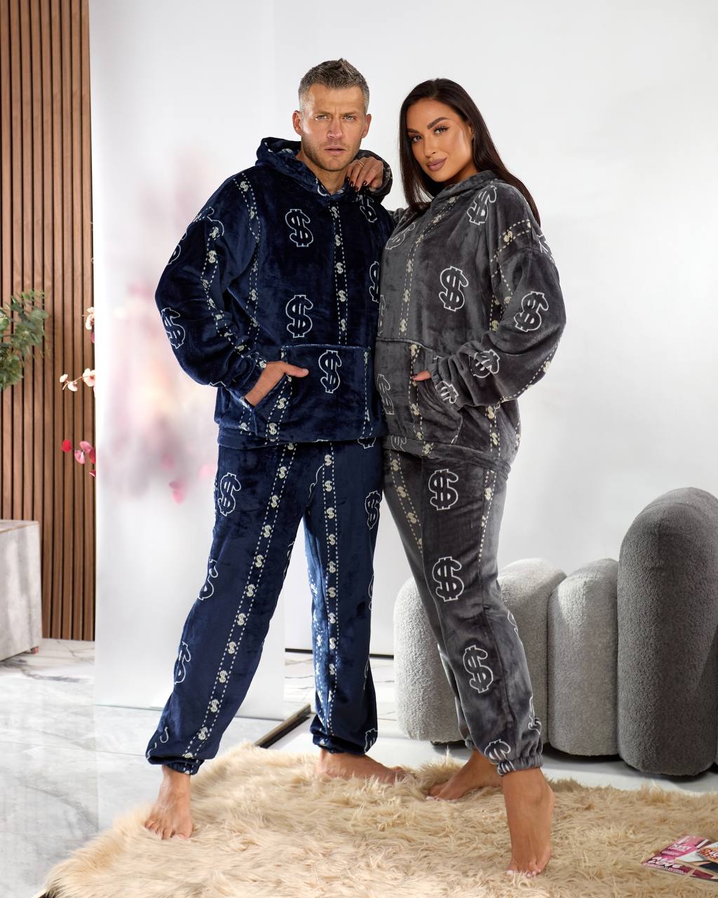 Two people wearing matching blue and gray pajama sets in a living room.