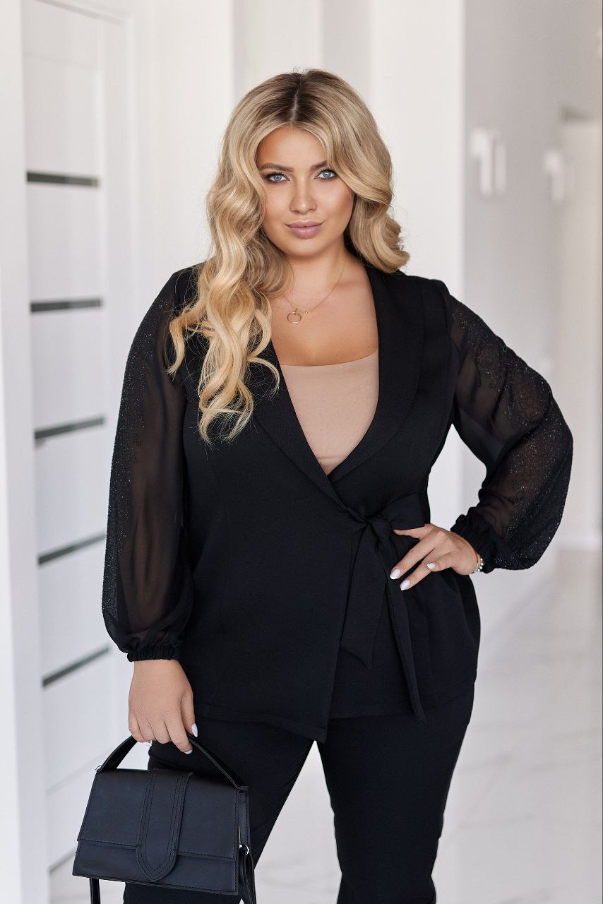 Woman wearing a black outfit with sheer sleeves against a white background