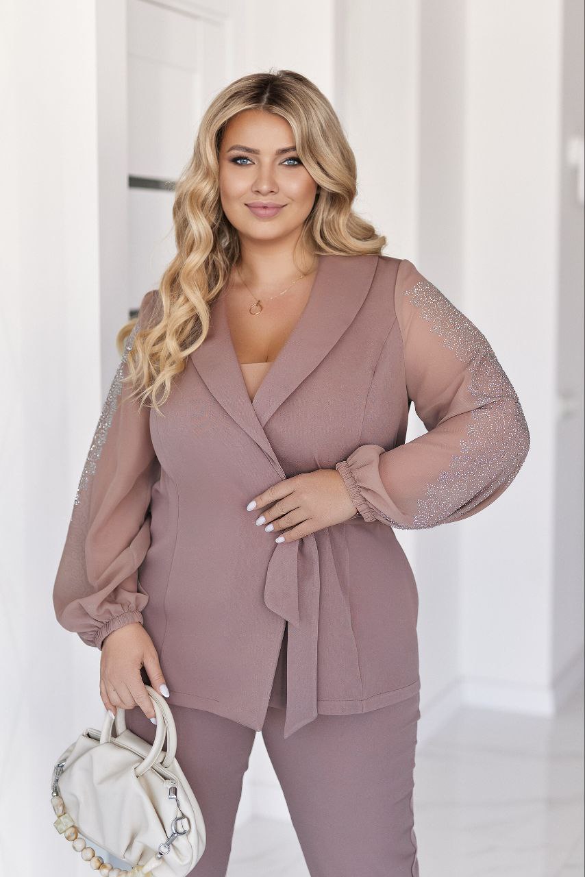Woman wearing a mauve outfit with sheer sleeves against a white background