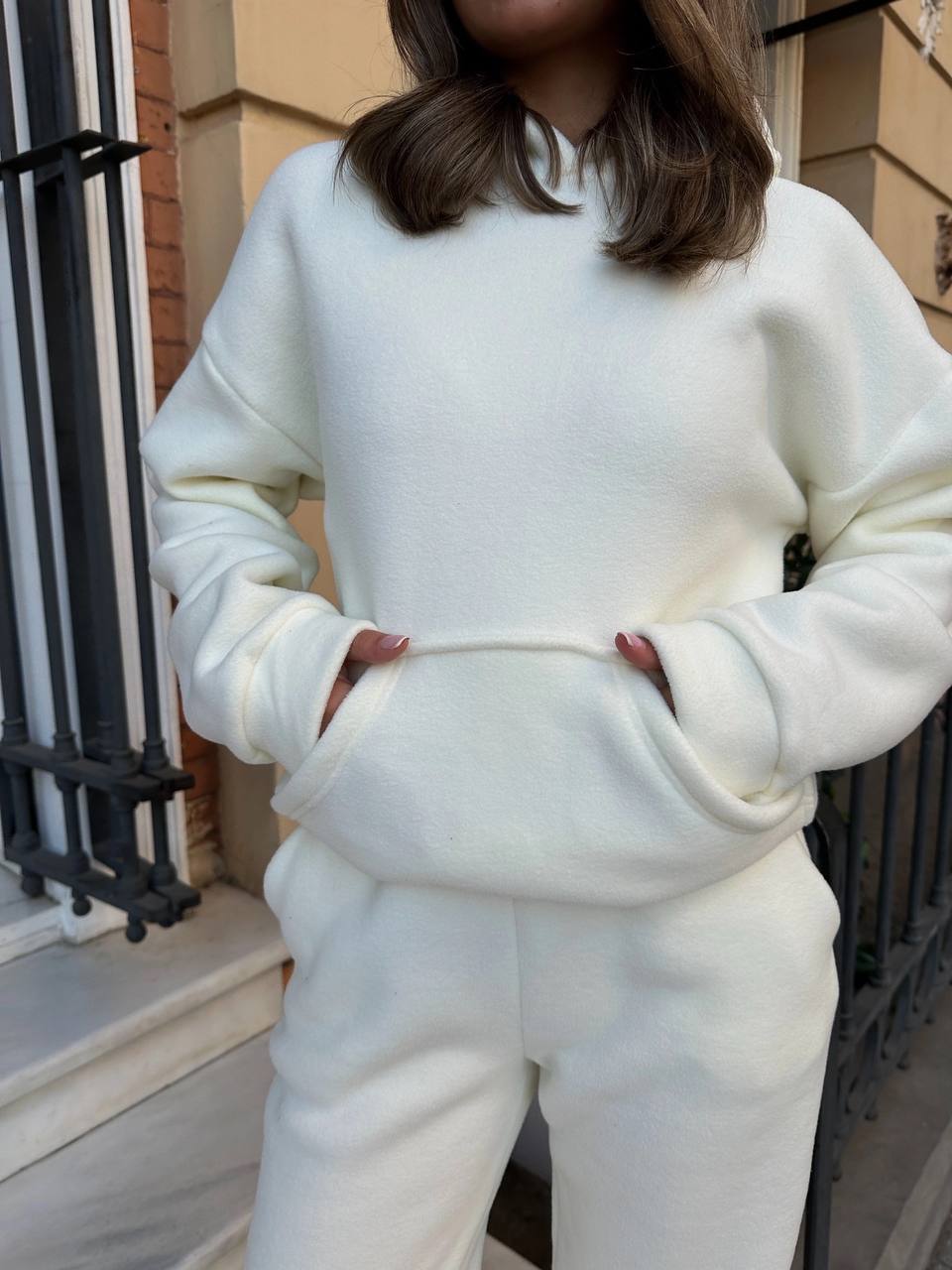 Person wearing a white sweatshirt and pants in an urban setting