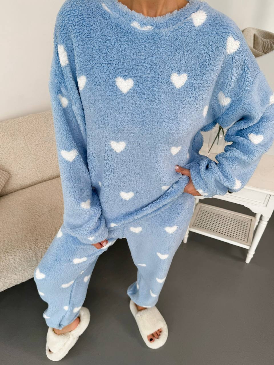 Blue pajama set with heart patterns worn by a person indoors.