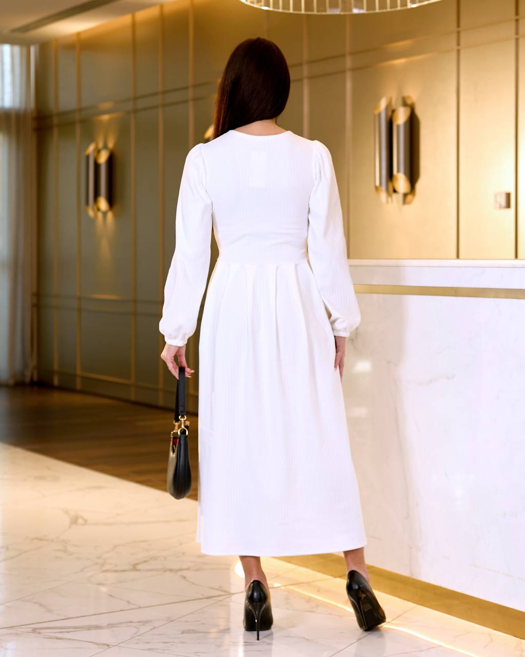 Woman in a white dress walking in an elegant interior setting