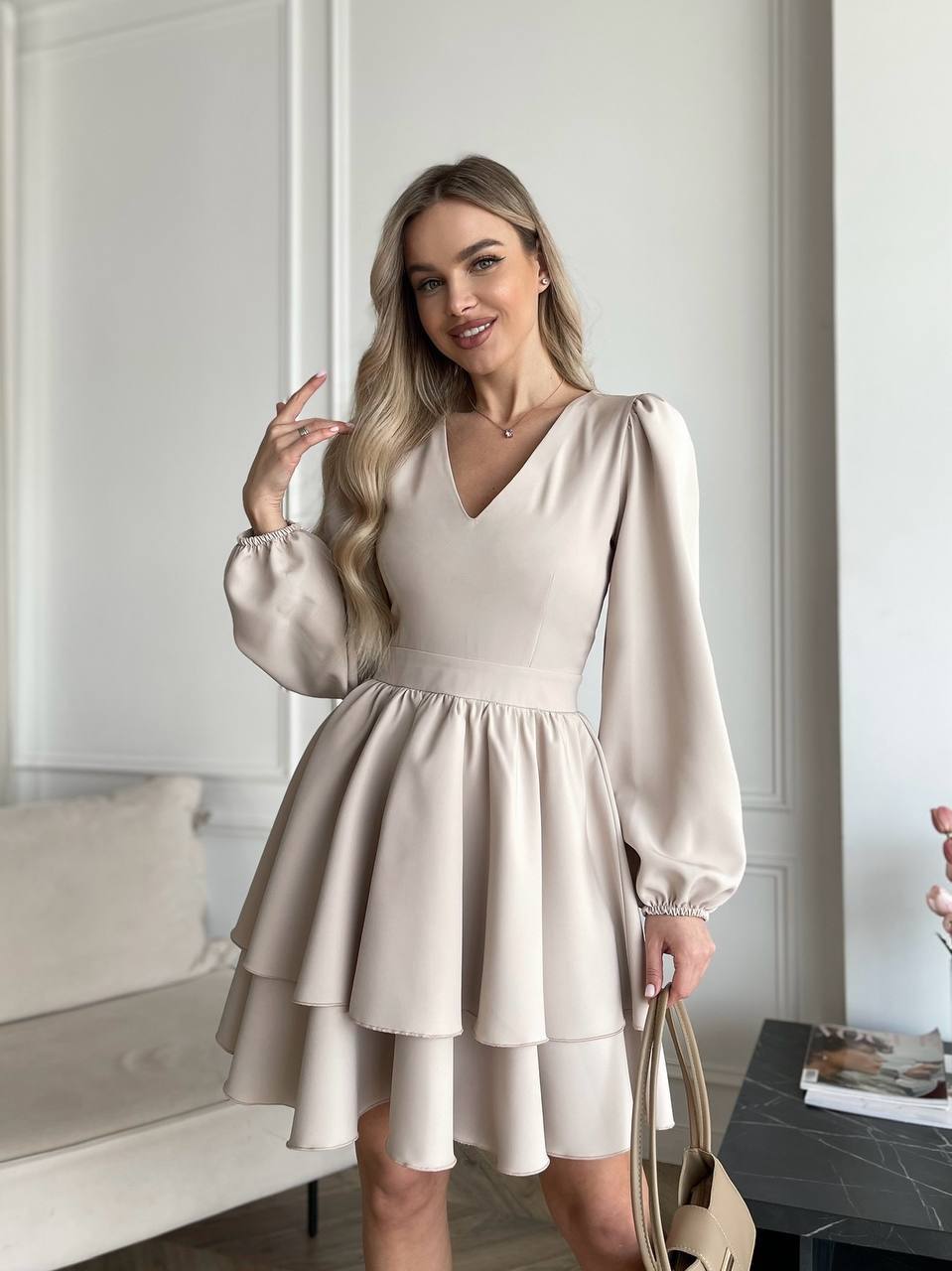 Woman wearing a beige dress with long sleeves in an indoor setting