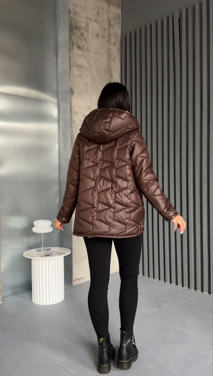 Person wearing a brown quilted jacket in an indoor setting