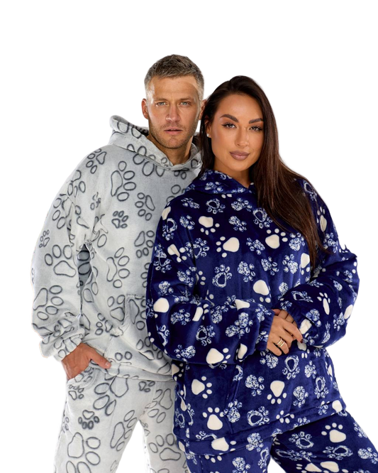 Two people wearing matching pajama sets with paw print patterns on a white background