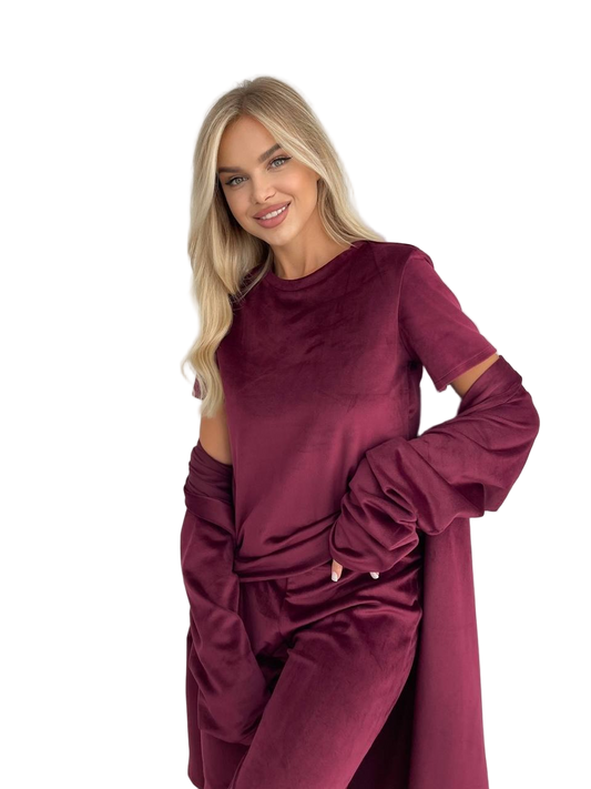 Woman wearing a burgundy outfit with cut-out sleeves on a white background