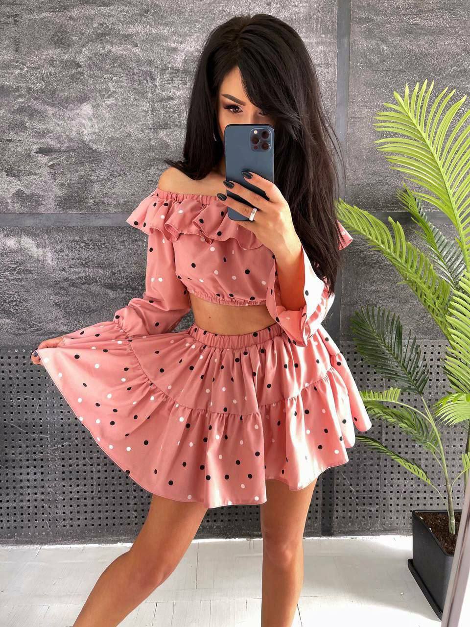 Woman taking a mirror selfie wearing a pink polka dot dress.
