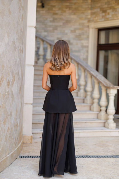 Woman wearing a black dress with sheer panels in an outdoor setting.