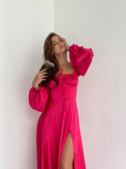 Woman wearing a bright pink dress with long sleeves against a white background