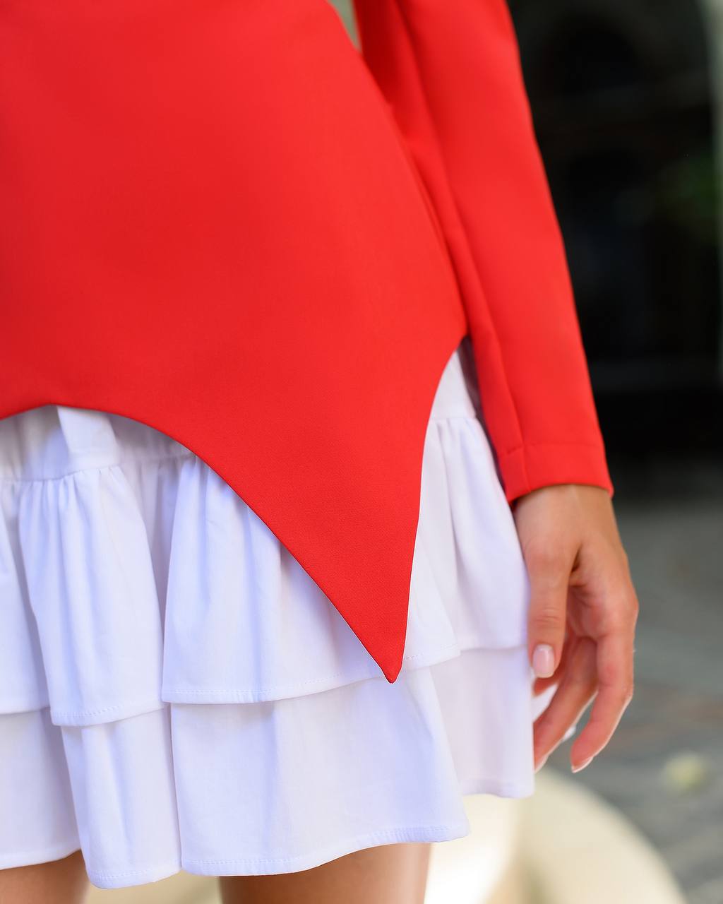 Red top and white skirt worn by a person, with a blurred background