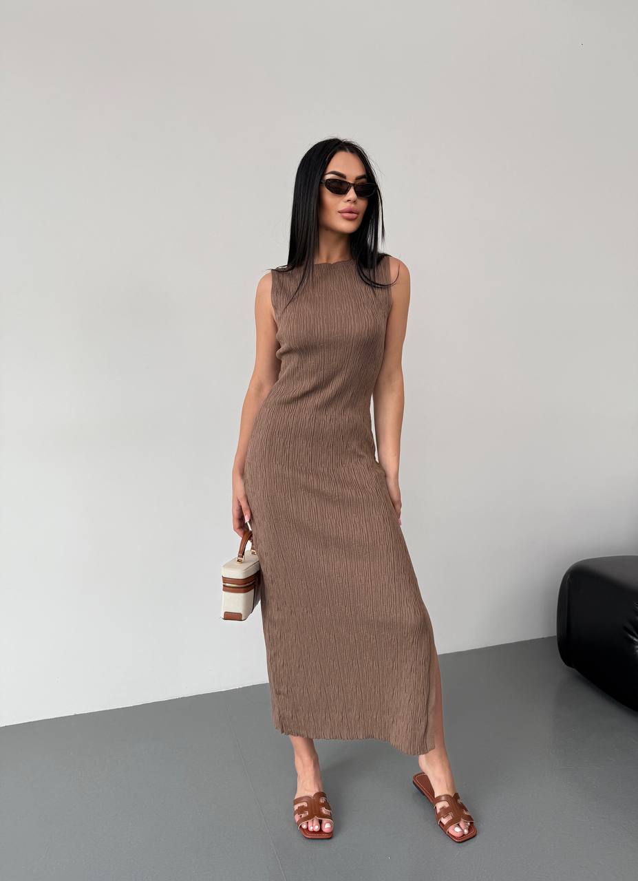 Woman wearing a brown sleeveless dress against a plain background