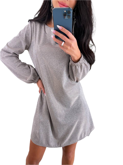 Woman wearing a gray long-sleeve dress holding a phone on a white background